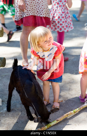 Ragazza stroking capra allo zoo Foto Stock