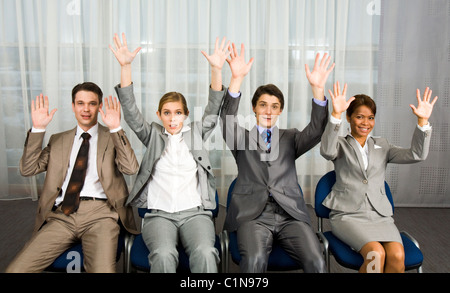 Ritratto di certi business group seduto in fila e alzando le braccia Foto Stock