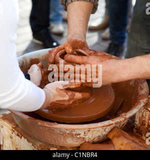 Potter insegna pentole da cucina il suo assistente. Close-up Foto Stock