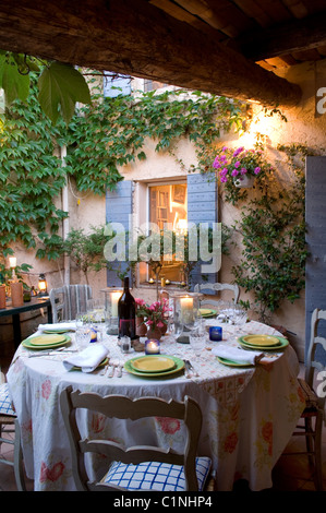 La cena prevista nel cortile di casa provenzale con ante e piante rampicanti Foto Stock