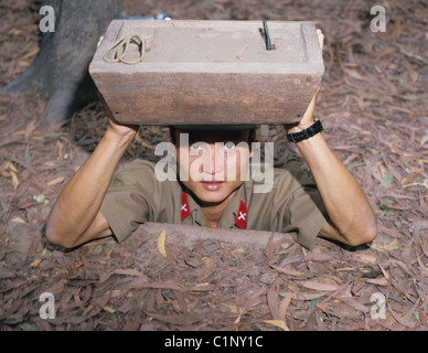 Soldato vietnamita guardando fuori da ingresso alla guerra del Vietnam tunnel. I Tunnel di Cu Chi. Ho Chi Minh city. Il Vietnam. Foto Stock