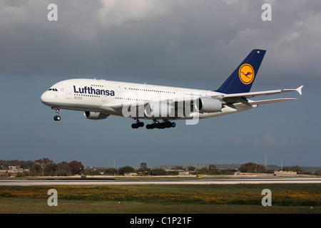 Commerciale viaggi dell'aria. Lufthansa Airbus A380 widebody grande aereo di linea in arrivo a Malta. Vista laterale che mostra il doppio ponte progettazione di questo aeromobile. Foto Stock