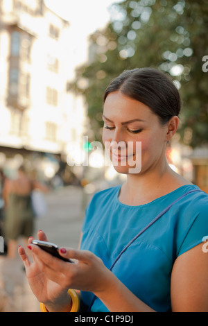 Donna di messaggistica di testo sul telefono cellulare, sorridente Foto Stock