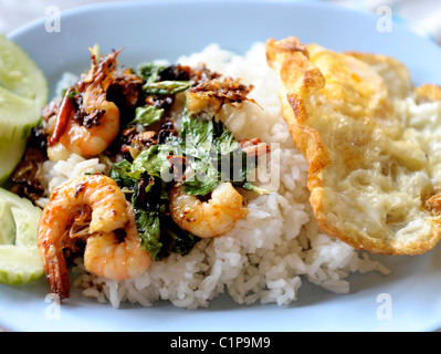 Mescolare gamberi fritti con basilico e uovo fritto top sul riso , tipico cibo durante la pausa pranzo a Bangkok, in Thailandia Foto Stock