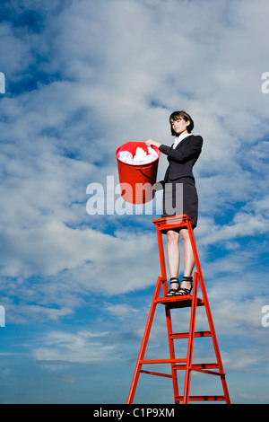 Donna buttare la spazzatura dal recipiente rosso permanente sulla scaletta Foto Stock