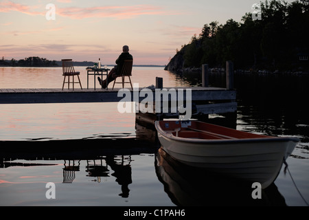 Silhouette di uomo seduto sul molo Foto Stock