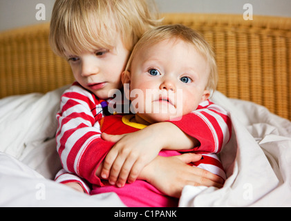 Ragazzo abbracciando la sorella sul letto Foto Stock