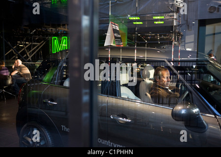 Interessato potenziale acquirente esplora un Mini concessionaria auto di Park Lane a Londra. Foto Stock