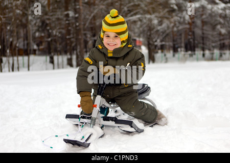 Il ragazzo sorridente si siede su una slitta Foto Stock