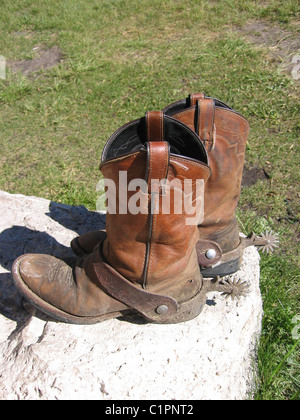 Stati Uniti d'America. Una coppia di polveroso, ben indossato stivali da cowboy di sedersi su una roccia, dopo una giornata di cavallo rigido, Idaho. Foto Stock