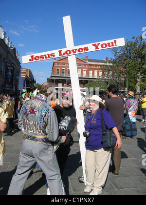 Gesù vi ama. Presso il Mardi Gras festival, New Orleans, religiosa adulta contestatori intervistato da un uomo vestito da re. Foto Stock