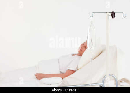 Donna anziana giacente in un letto di ospedale Foto Stock