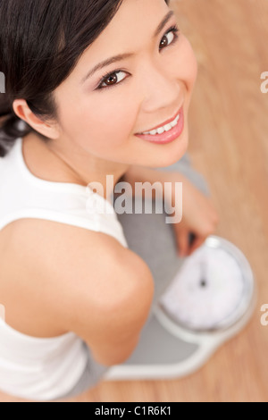 Sopra la testa vista di felice & bella asiatica orientale donna cinese del peso di se stessa su scale in palestra o club salute Foto Stock