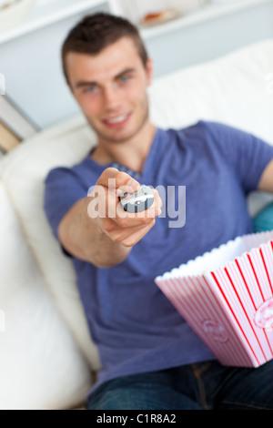 Uomo sorridente è rilassante nel salotto con popcorn Foto Stock