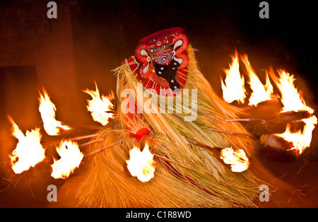 Performer Theyyam circondato da torce fiammeggianti danze una variazione del rito del fuoco eseguita in festival nel nord del Kerala. Foto Stock