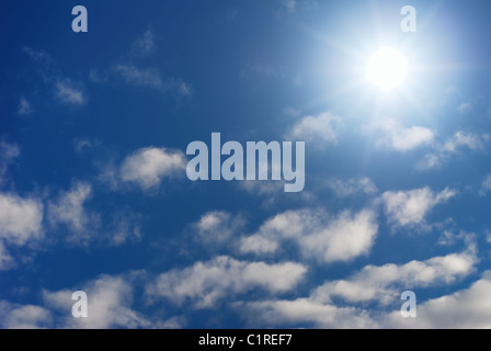 Sun splendenti in un cielo azzurro con poche nuvole bianche Foto Stock