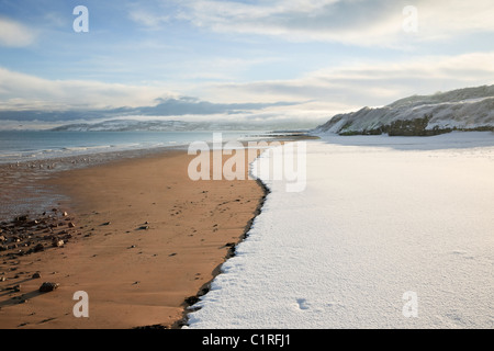 Vista lungo la spiaggia sabbiosa vuota con neve sopra la maree mark nell'inverno 2010. Benllech, Isola Di Anglesey, Galles Del Nord, Regno Unito, Gran Bretagna Foto Stock