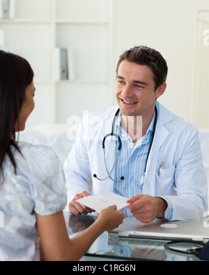 Medico sorridente dando una prescrizione per il suo paziente femmina Foto Stock