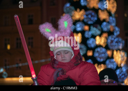 Ragazza giovane con toy baton, rosa orecchie di coniglietto, portato piggyback dalla casa madre, alla vigilia di Capodanno concerto all'aperto a Wroclaw in Polonia Foto Stock