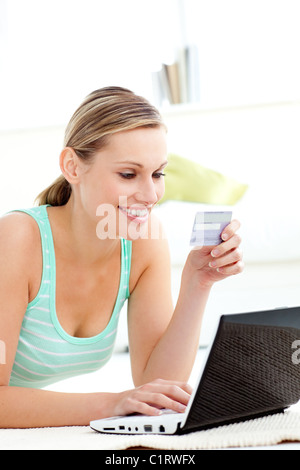 Accattivante giovane donna con il suo computer portatile in possesso di una carta di soggiorno Foto Stock