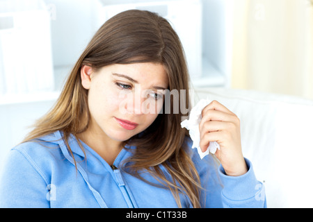 Triste donna giovane azienda tessuti seduto in salotto Foto Stock