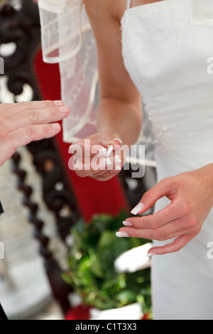 Sposa di mettere l'anello di matrimonio su sposa stallieri dito Foto Stock