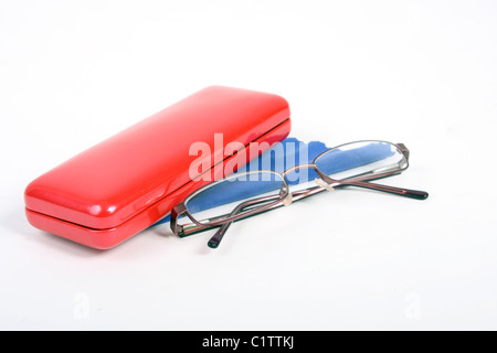 Una coppia di borgogna gli occhiali da lettura su un bianco di fondo tagliato con un rosso custodia per occhiali e panno blu per pulizia. Foto Stock