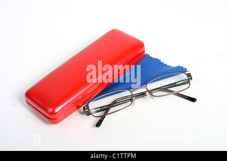 Una coppia di borgogna gli occhiali da lettura su un bianco di fondo tagliato con un rosso custodia per occhiali e panno blu per pulizia. Foto Stock