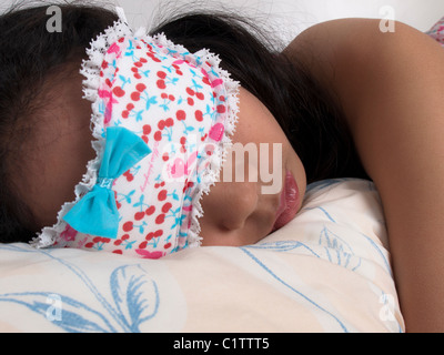 Una ragazza dorme con una mascherina a. Foto Stock