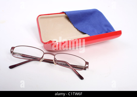 Una coppia di borgogna gli occhiali da lettura su un bianco di fondo tagliato con un rosso custodia per occhiali e panno blu per pulizia. Foto Stock