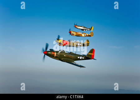 Una campana P-63 Kingcobra, due Curtiss P-40N Warhawk, e un North American P-51D Mustang in volo nei pressi di Chino, California. Foto Stock