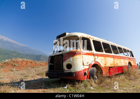 Stripped arrugginito, vecchio abbandonato bus rosso relitto in arido paesaggio montuoso del Montenegro Foto Stock