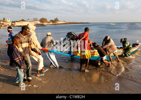 Gli uomini tirando una piroga senegalesi a riva. Dakar, Senegal Africa Foto Stock