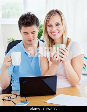 Coppia giovane a bere caffè e lavorare insieme sul laptop Foto Stock