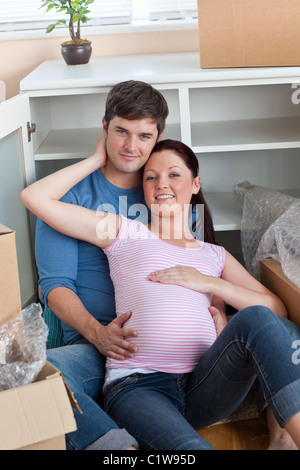 Coppia felice nella loro nuova casa seduta sul pavimento tra le scatole di cartone Foto Stock