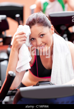Donna attraente tergi il suo viso dopo esercizi su una bicicletta in un centro sportivo Foto Stock