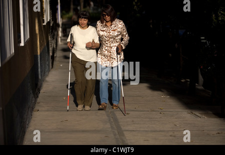 Fotografi ciechi camminare sul marciapiede utilizzando canne durante un workshop di fotografia per non vedenti e ipovedenti Foto Stock