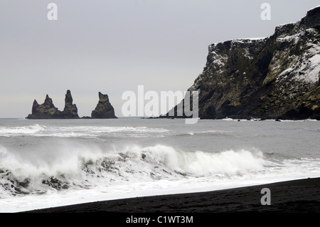 Spiaggia di sabbia nera, il mare Reynisdrangar pile e il Reynnisfjall montagna vicino a Vik nella costa meridionale dell'Islanda Foto Stock