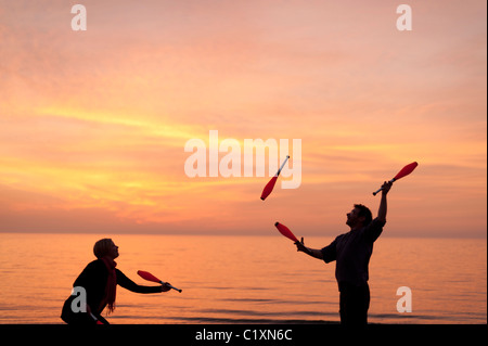 Un uomo e una donna la giocoleria sulla spiaggia al tramonto, serata primaverile, Aberystwyth Wales UK Foto Stock