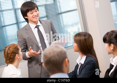 Foto di fiduciosa imprenditore attività spiegando ai suoi colleghi in ufficio Foto Stock