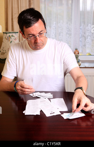 Uomo adulto il controllo dei suoi introiti da negozi e quante cose costano durante la recessione Foto Stock