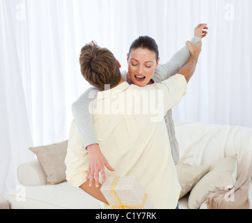 Excited donna recuperando un presente nascosto dietro il suo fidanzato Foto Stock