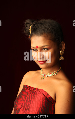 Un sorridente modello indiano rivestito in rosso senza spalline camicetta,gold jewelery Foto Stock