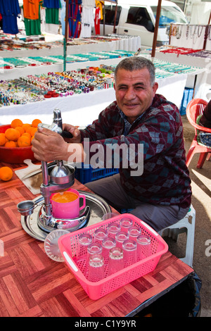 Bagno turco uomo vendita di succo d'arancia fresco utilizzando uno spremi agrumi al bazaar in Belek, Turchia Foto Stock