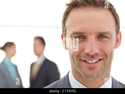 Allegro imprenditore in posa davanti al suo compagno di squadra mentre si lavora Foto Stock