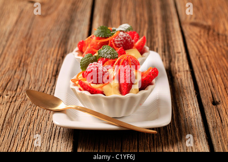 Budini cremosi e frutta fresca in piccoli piatti da dessert Foto Stock