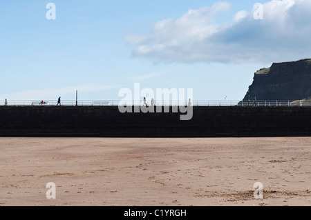 Una vista del nuovo molo di pietra a Whitby da una spiaggia di sabbia in una luminosa giornata di sole. Foto Stock