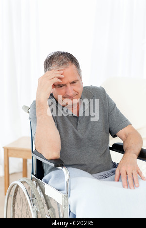 Senior nella sua sedia a rotelle con un mal di testa Foto Stock