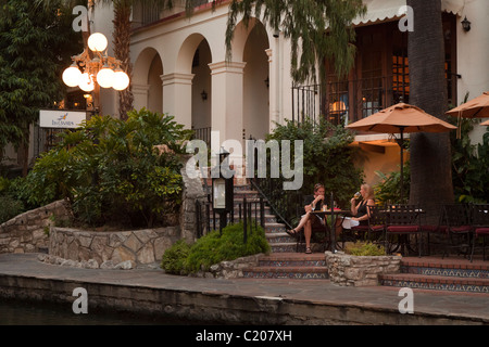 Due persone di mangiare e di bere il vino sul fiume San Antonio a piedi Texas USA Foto Stock