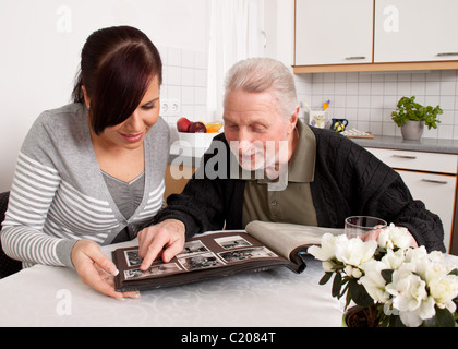 Donna guarda a un album di foto con gli anziani Foto Stock